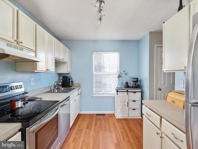 kitchen featuring light hardwood / wood-style floors, sink, appliances with stainless steel finishes, and track lighting