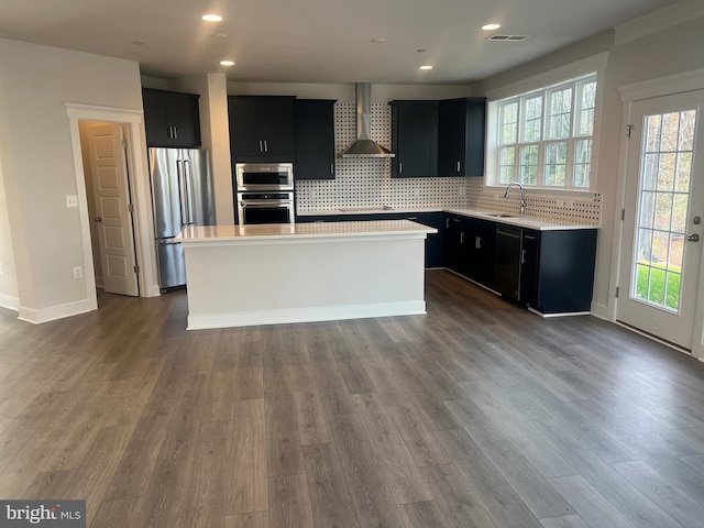 kitchen with wall chimney exhaust hood, a center island, sink, and appliances with stainless steel finishes