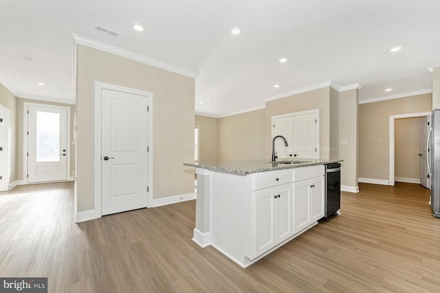 kitchen with white cabinets, light hardwood / wood-style floors, sink, light stone counters, and a center island with sink