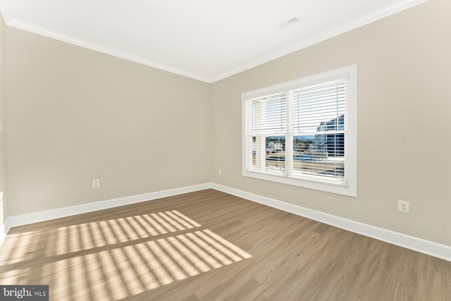 empty room with crown molding and light hardwood / wood-style flooring