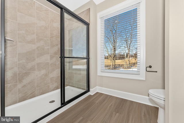 bathroom featuring hardwood / wood-style flooring, toilet, and a shower with shower door