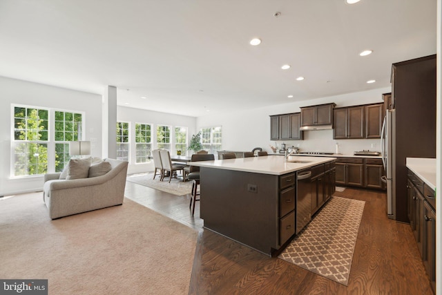 kitchen featuring sink, dark hardwood / wood-style flooring, an island with sink, a kitchen bar, and appliances with stainless steel finishes