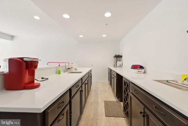 kitchen with dark brown cabinetry, sink, and light tile patterned floors