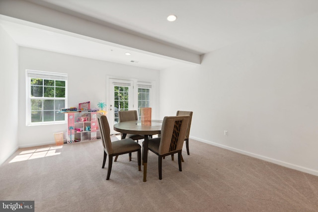 carpeted dining area with beam ceiling and plenty of natural light