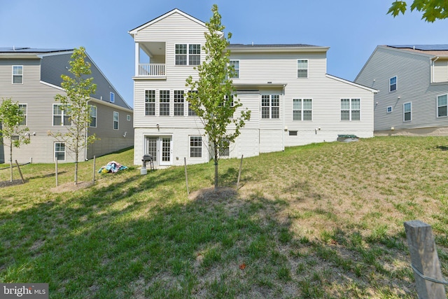 rear view of house featuring a yard and a balcony