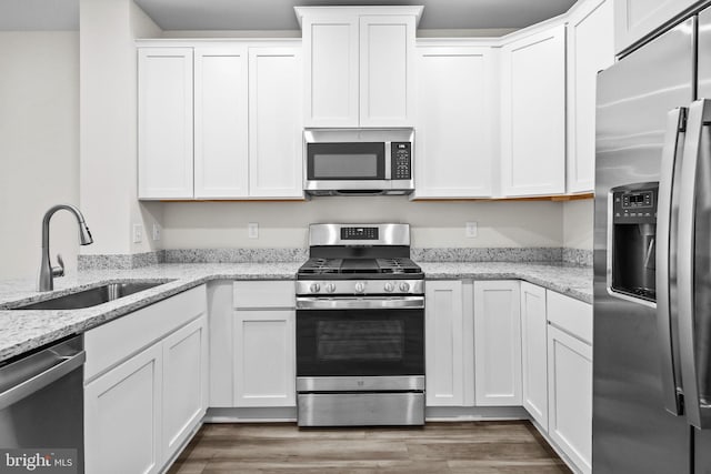 kitchen with white cabinetry, sink, stainless steel appliances, and light stone counters