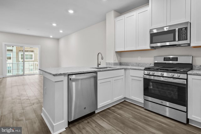 kitchen with kitchen peninsula, sink, white cabinets, and stainless steel appliances