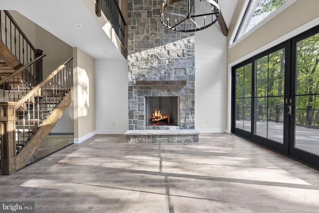 unfurnished living room with a fireplace, french doors, a chandelier, and high vaulted ceiling