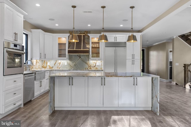 kitchen with a center island, appliances with stainless steel finishes, pendant lighting, white cabinets, and custom exhaust hood