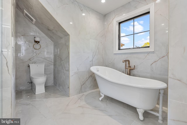 bathroom featuring a bath, toilet, and tile walls