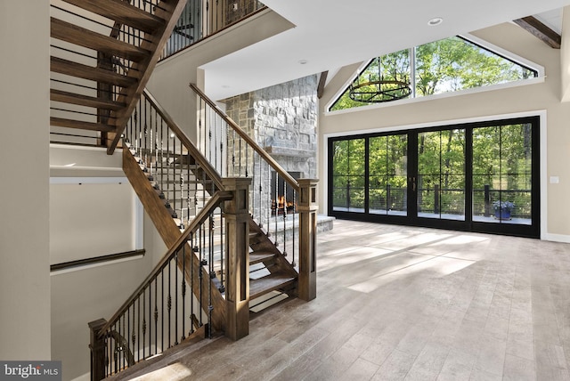 staircase with french doors, high vaulted ceiling, wood-type flooring, and plenty of natural light