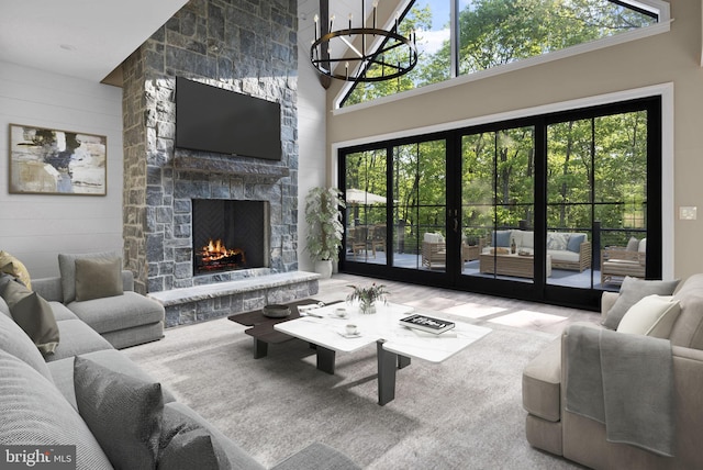 living room with a fireplace, high vaulted ceiling, a chandelier, and french doors