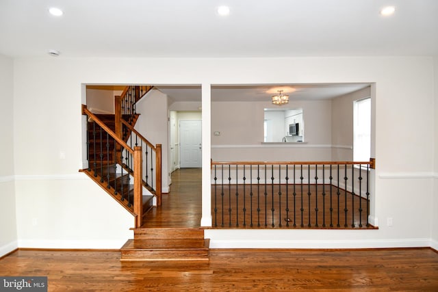 staircase featuring hardwood / wood-style floors and a notable chandelier