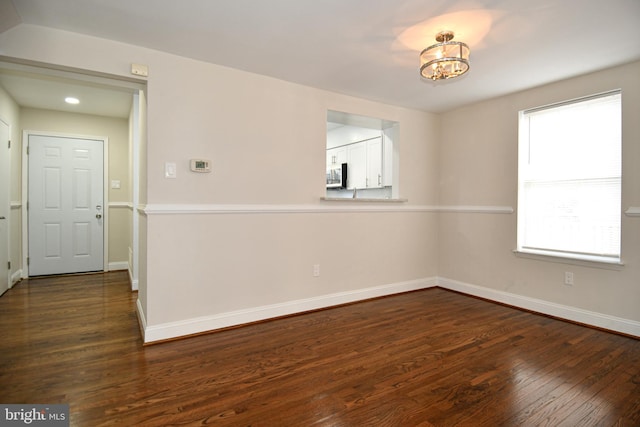 unfurnished room with a chandelier and dark wood-type flooring