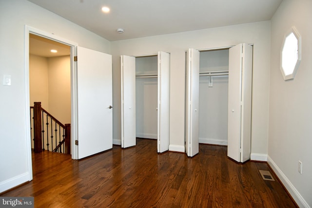 unfurnished bedroom featuring dark hardwood / wood-style floors and two closets