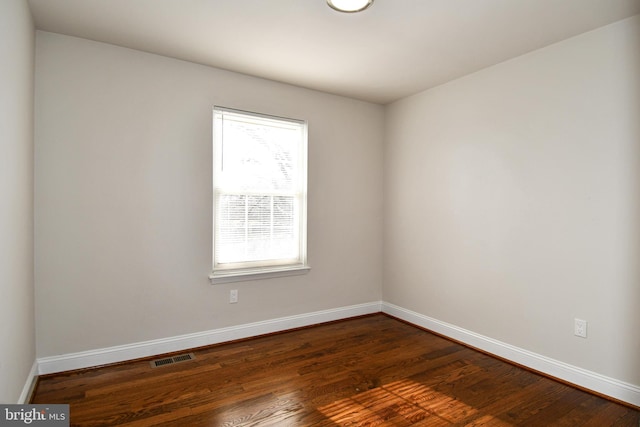 spare room featuring plenty of natural light and dark wood-type flooring