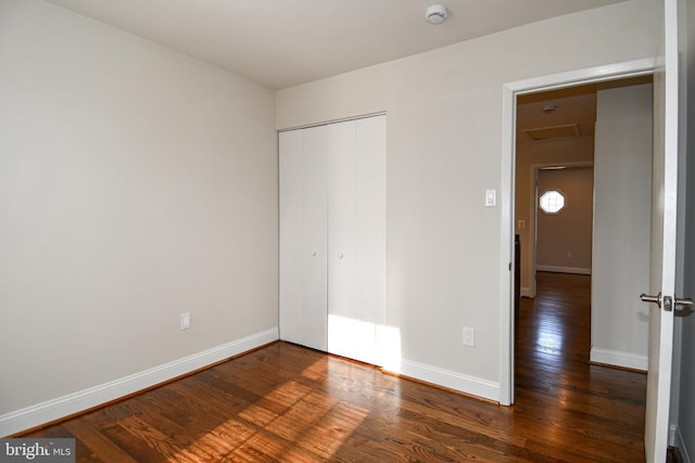 unfurnished bedroom with dark hardwood / wood-style flooring and a closet