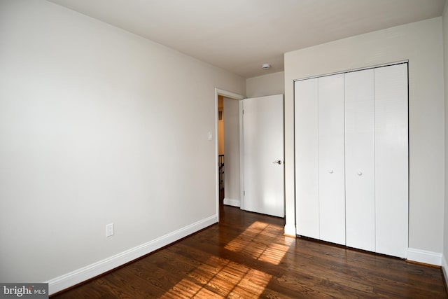 unfurnished bedroom featuring a closet and dark hardwood / wood-style floors