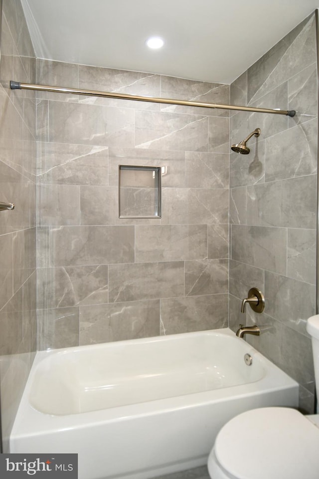 bathroom featuring tiled shower / bath combo and toilet