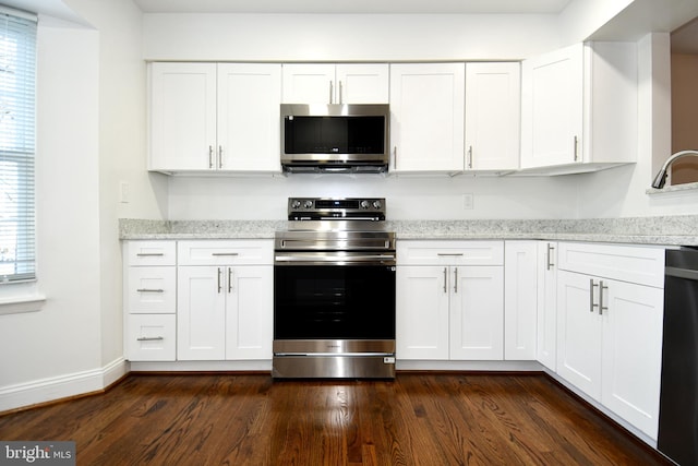 kitchen featuring white cabinets, dark hardwood / wood-style flooring, stainless steel appliances, and light stone countertops