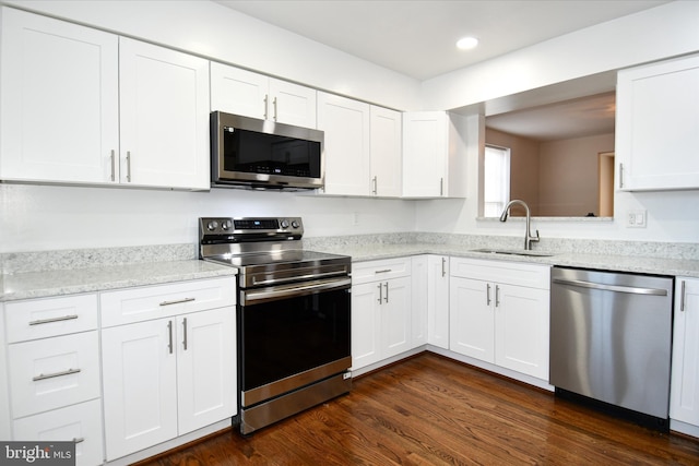 kitchen with white cabinetry, sink, stainless steel appliances, light stone counters, and dark hardwood / wood-style flooring