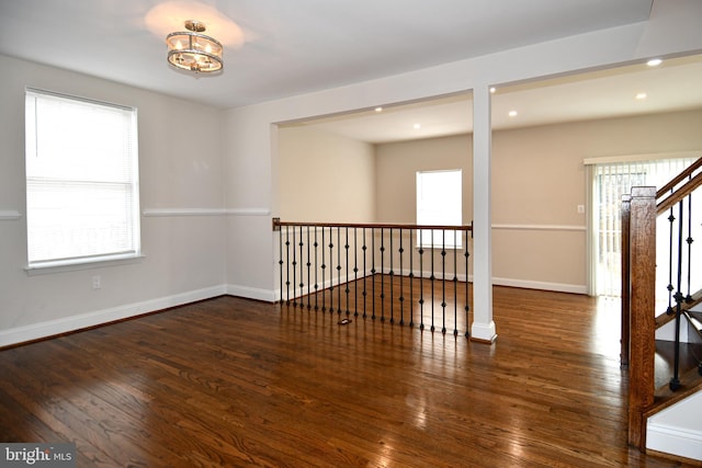 spare room with a notable chandelier and dark hardwood / wood-style flooring