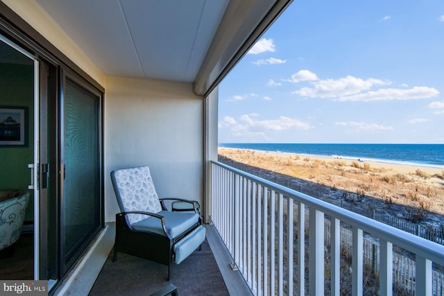 balcony featuring a view of the beach and a water view