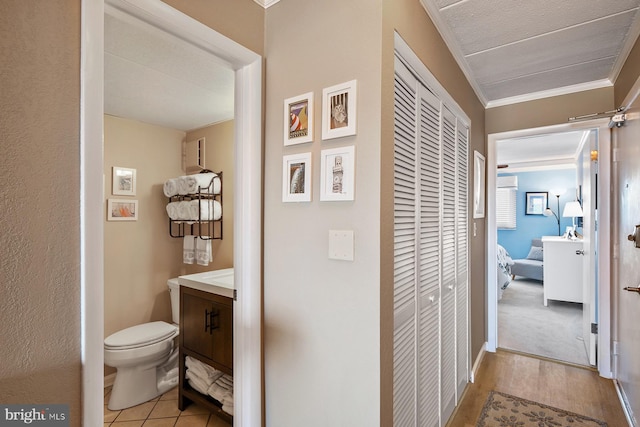 bathroom with hardwood / wood-style flooring, vanity, toilet, and ornamental molding