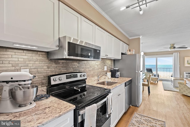 kitchen featuring appliances with stainless steel finishes, tasteful backsplash, ceiling fan, a water view, and white cabinetry