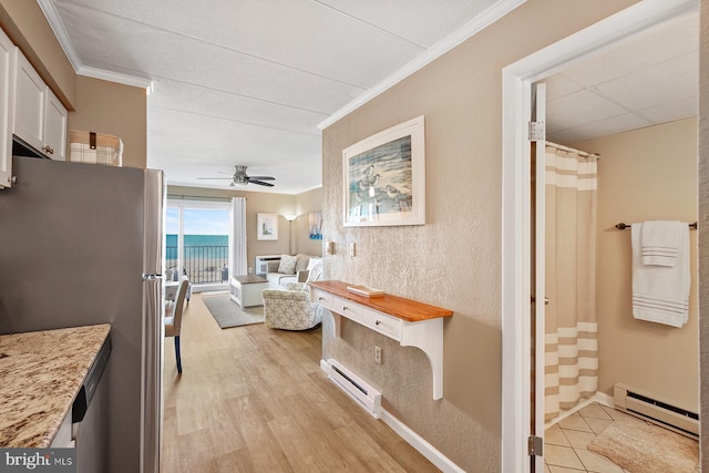 corridor with light hardwood / wood-style floors, a water view, ornamental molding, and a baseboard heating unit