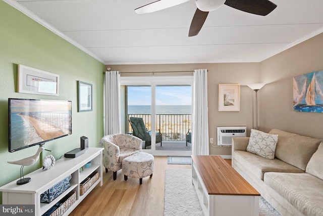 living room with ceiling fan, a wall mounted AC, light wood-type flooring, a water view, and ornamental molding