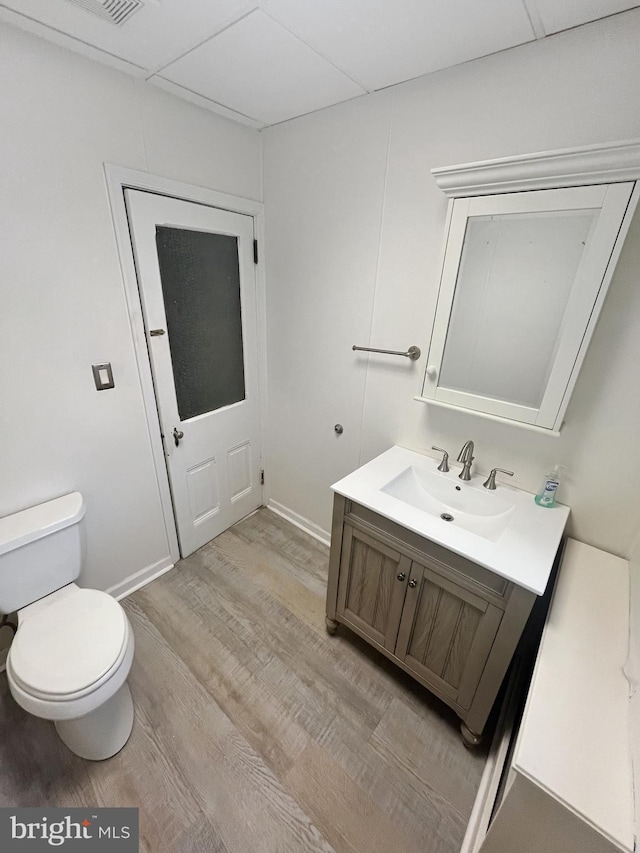 bathroom with a paneled ceiling, vanity, toilet, and wood-type flooring