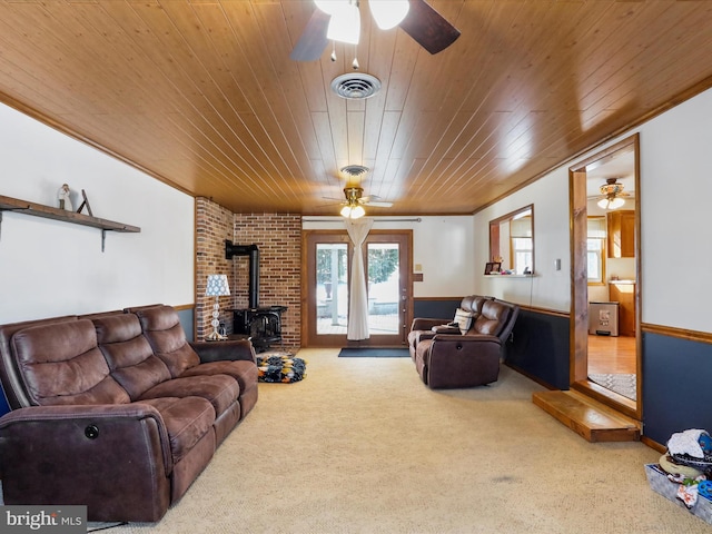 carpeted living room with a wood stove, ornamental molding, and wood ceiling