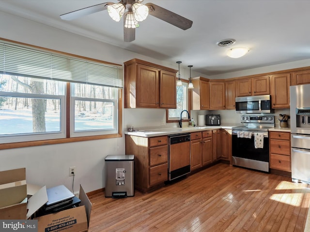 kitchen with ceiling fan, sink, hanging light fixtures, light hardwood / wood-style floors, and appliances with stainless steel finishes