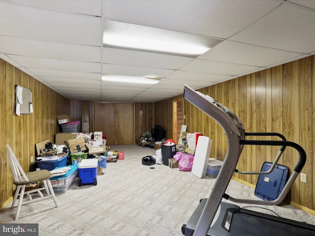 exercise area featuring wood walls, a drop ceiling, and carpet floors