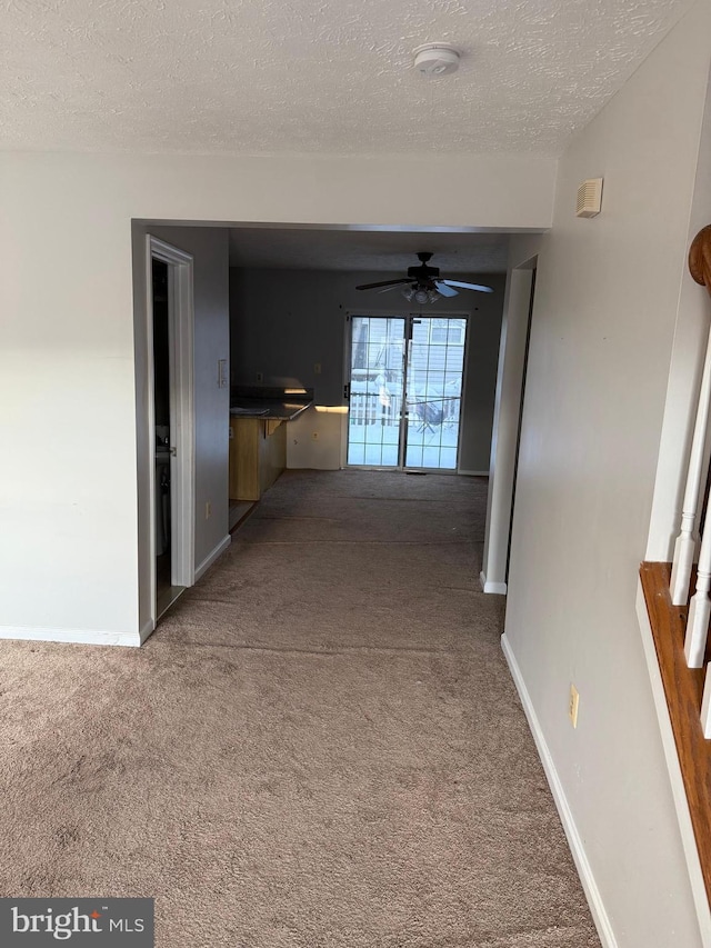 hall featuring a textured ceiling and carpet floors