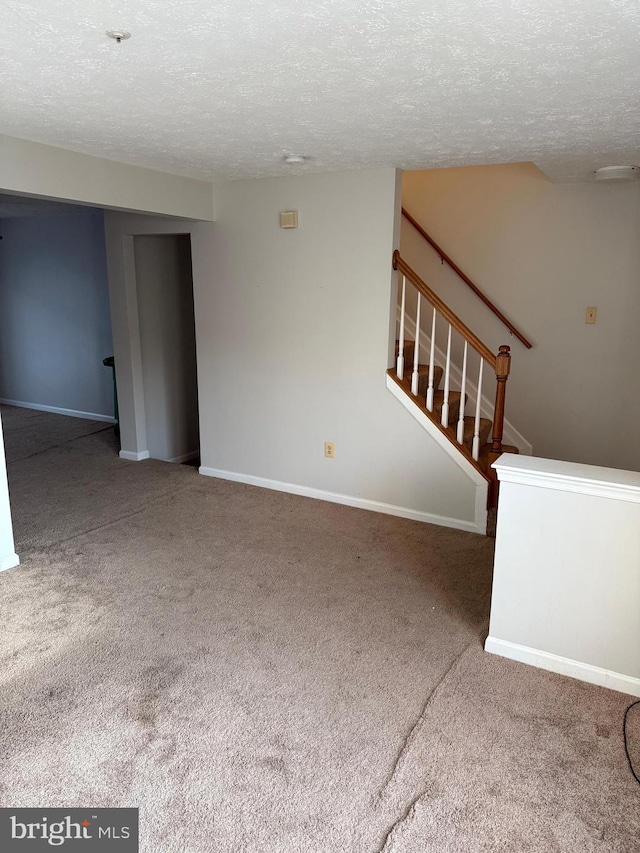 unfurnished living room with carpet flooring and a textured ceiling