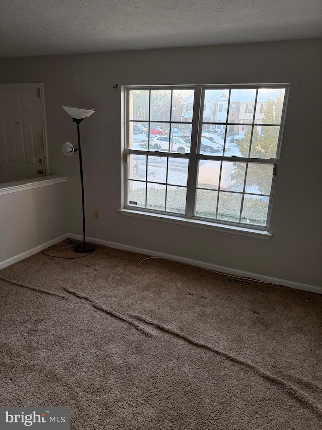 carpeted empty room featuring a textured ceiling