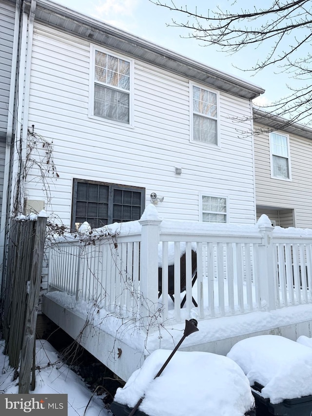 snow covered back of property featuring a deck