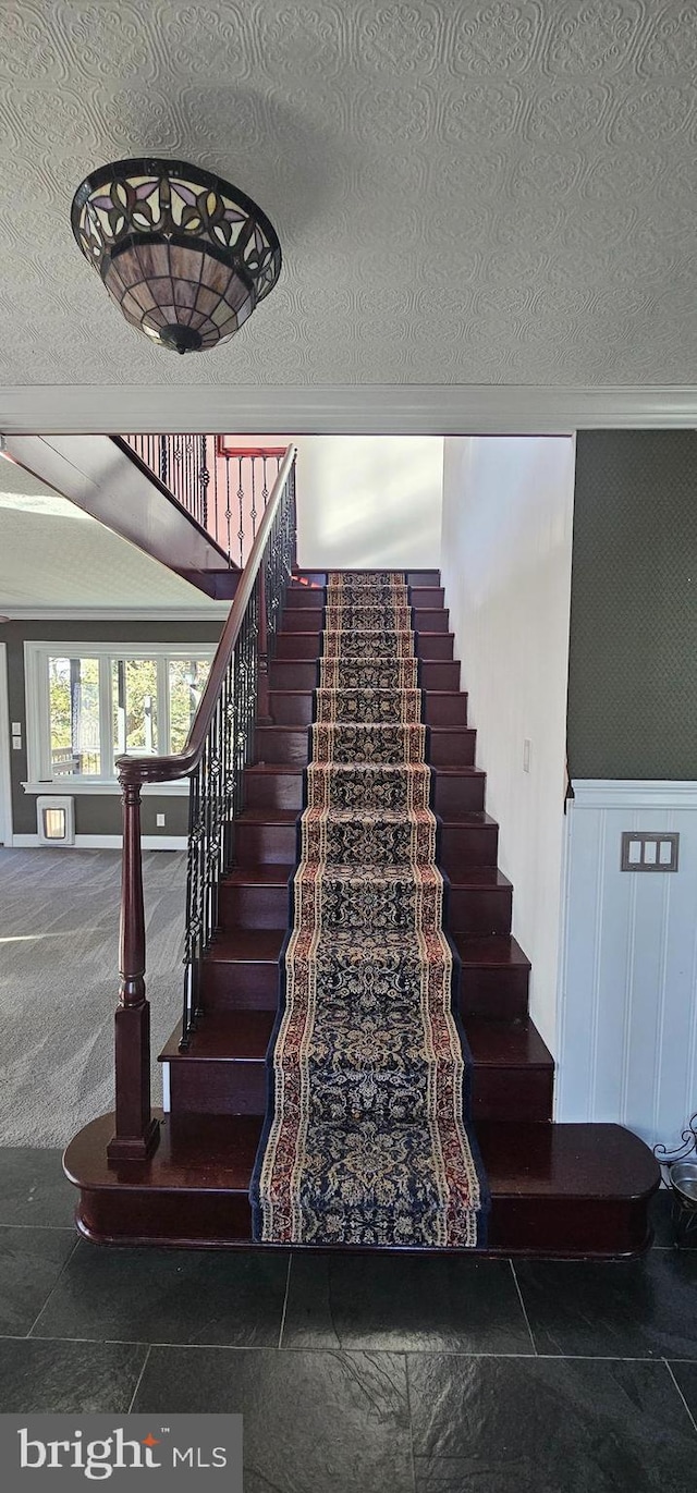 staircase with carpet, ornamental molding, and a textured ceiling