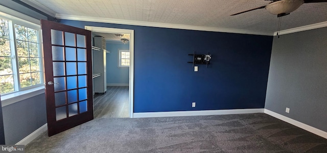 carpeted empty room featuring ceiling fan, crown molding, and a wealth of natural light