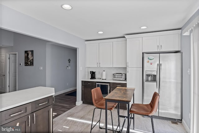 kitchen featuring white cabinets, decorative backsplash, dark brown cabinets, stainless steel fridge with ice dispenser, and beverage cooler