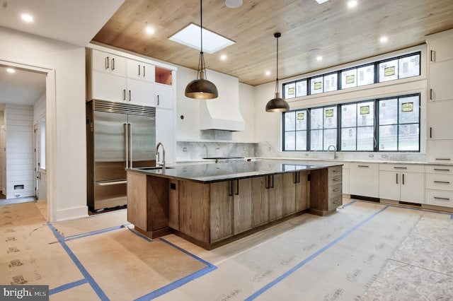 913 Drexel Ln, Bryn Mawr, PA 19010 - kitchen with built in fridge, wooden ceiling, a large island with sink, tasteful backsplash, and white cabinetry
