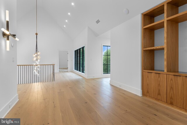 913 Drexel Ln, Bryn Mawr, PA 19010 - unfurnished living room featuring high vaulted ceiling, a chandelier, light wood-style floors, and baseboards
