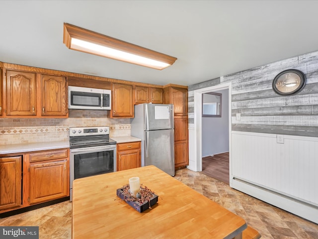 kitchen featuring wooden counters, decorative backsplash, stainless steel appliances, baseboard heating, and wooden walls