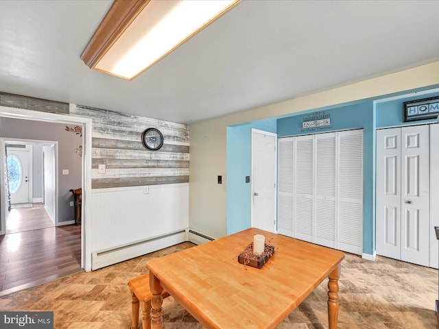 dining room with wood walls and a baseboard heating unit