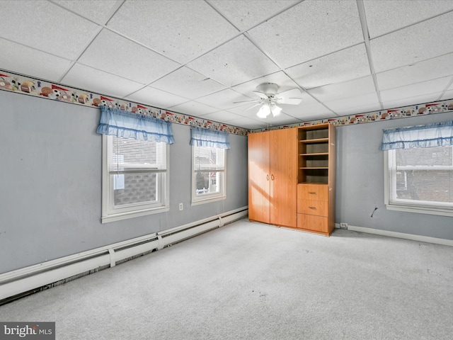 unfurnished room featuring a paneled ceiling, ceiling fan, light colored carpet, and a baseboard heating unit