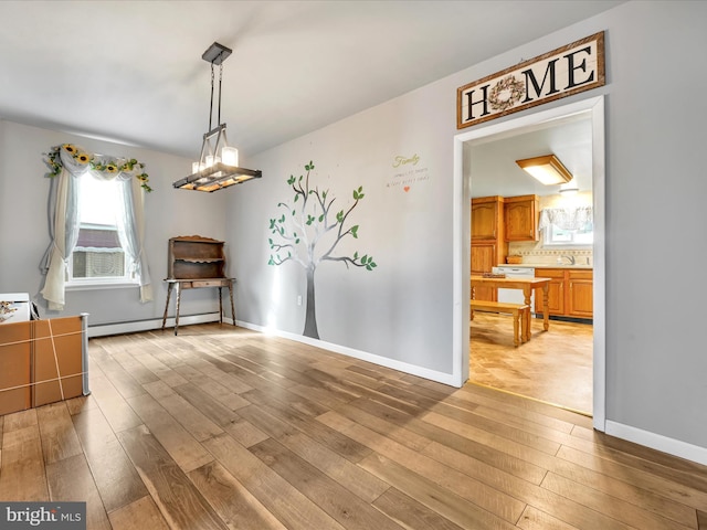 dining area with light wood-type flooring, sink, and a baseboard radiator