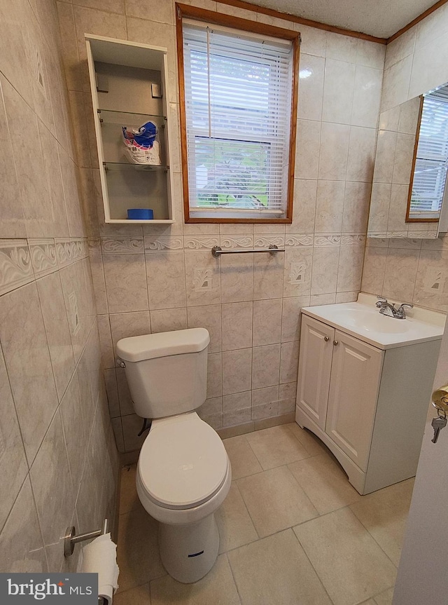 bathroom with vanity, tile patterned floors, toilet, ornamental molding, and tile walls