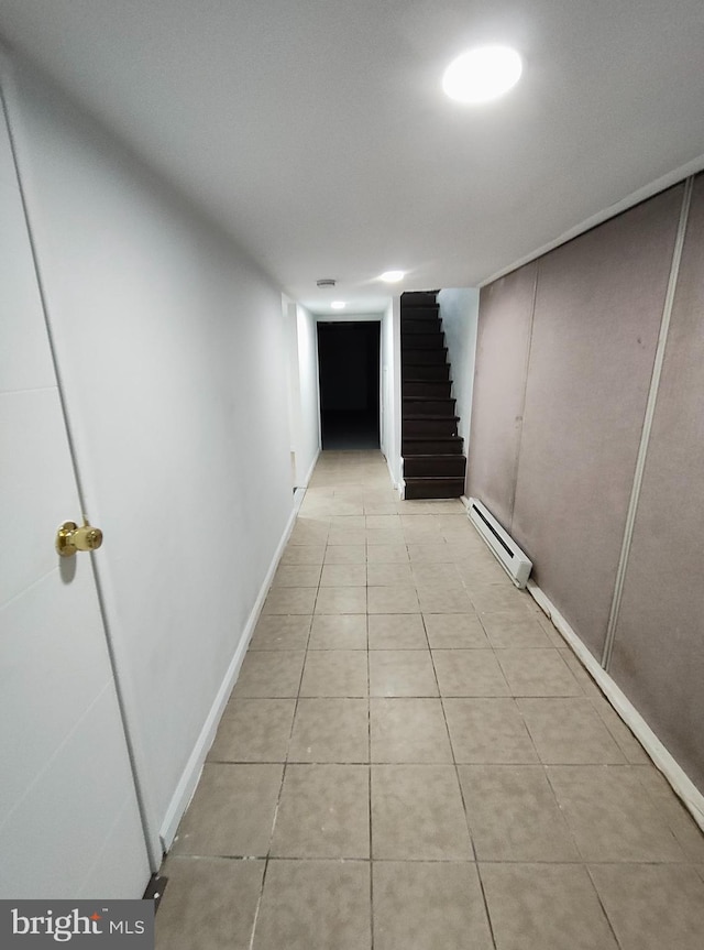 hallway with light tile patterned floors and a baseboard heating unit